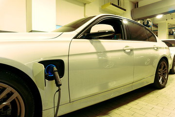 Electric car charging on parking lot with electric car charging station on supermarket in city . Close up of power supply plugged into an electric car charging.	