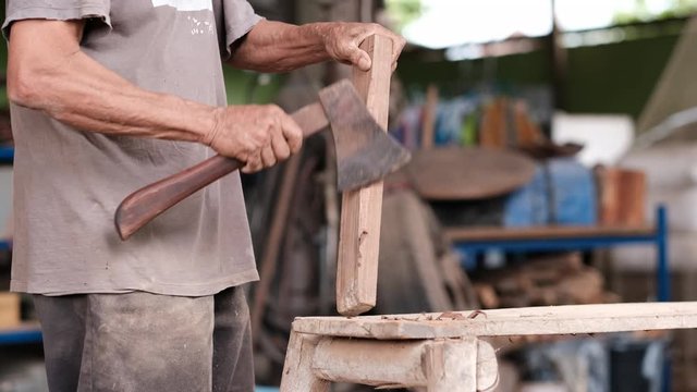 Craftsman use ax to produce handheld of the other new ax in workplace area. 
