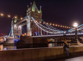 Obraz premium person looking at the tower bridge at night