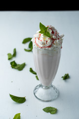 Classic vanilla milkshake with whipped cream isolated on white flat lay with mint leaves around