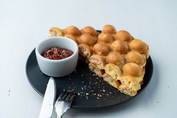 Close up of Hong Kong bubble waffle with sausage and cheese on white flat lay