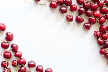 Frame of red cherries on a white background. View from above. For design themes of fresh berries and fruits, food, health. Image with copy space for text.