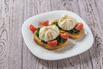 Poached eggs with tomatoes and fried greens on toasted bread.