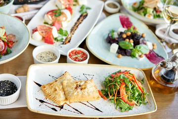 Latin American fried empanadas with Vegetable salad with arugula. Variety of dishes on the table. Various snacks and antipasti on the table. Restaurant menu. Italian cuisine