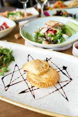 Latin American fried empanadas with Vegetable salad with arugula. Variety of dishes on the table. Various snacks and antipasti on the table. Restaurant menu. Italian cuisine