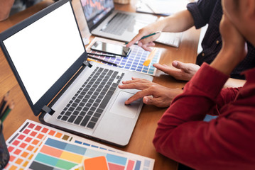 Blank white laptop screen of graphic designers put on desk table in co-working space