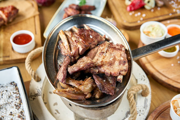 Various grilled meat set heated on coals. Barbecue restaurant menu. Many different food on the table. Dinner party or Banquet