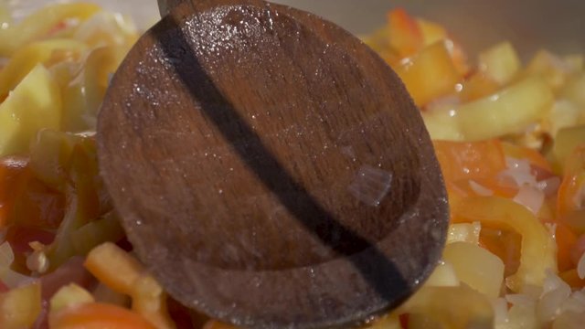Stirring up a pile of tomatoes and pepper in a cauldron with a wooden spoon during the preparation of cooking letcho - 180 fps slow motion