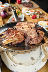 Various grilled meat set heated on coals. Barbecue restaurant menu. Many different food on the table. Dinner party or Banquet