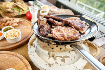 Various grilled meat set heated on coals. Barbecue restaurant menu. Many different food on the table. Dinner party or Banquet