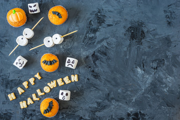 Halloween pumpkin cupcakes served on black background with happy Halloween sentence