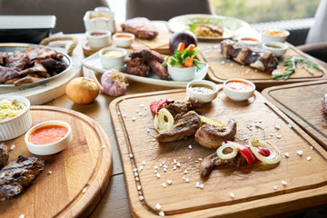 Lamb tongue kebab with Pickled cabbage and two sauces. Barbecue restaurant menu. Many different food on the table. Dinner party or Banquet