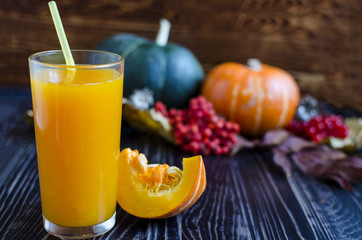 a glass of pumpkin juice with a pumpkin straw in the background