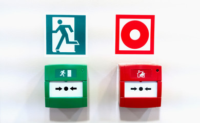 Alarming green emergency exit button and red fire alarm.
