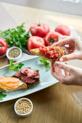 Woman hold in hands Bruschetta with tomatoes. Variety of dishes on the table. Italian cuisine