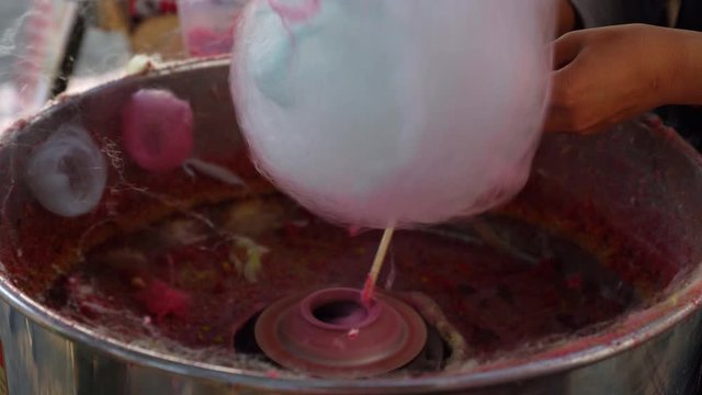 closeup making cotton candy with hand rolling in machine