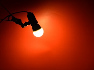 bright light from a LED light bulb on a red background in a dark atmosphere
