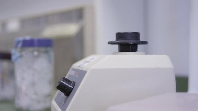 Clinical laboratorist putting  putting liquid beakers on centrifuge shaker.
