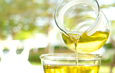 Pouring olive oil in the a glass bowl at stone kitchen and inside green garden view. Prepare for cooking concept. Healthcare and Beauty Concept.