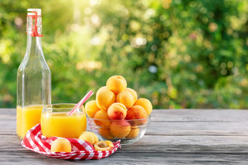 Apricot juice in bottle and glass and apricots on a wooden table