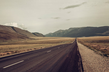 the road goes into the distance towards the snowy mountains