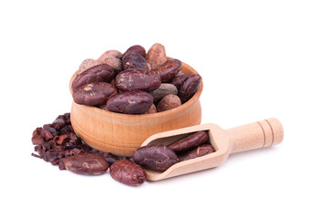 Peeled cocoa beans in the wooden bowl, isolated on white background. Roasted and aromatic cocoa beans in wooden spoon, natural chocolate.