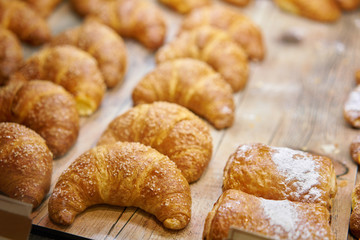 many of croissants. Hot pastries lie on the showcase in the cafe. Buns and bagels in the store.