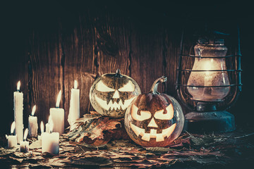 Halloween pumpkin with glowing face on a wooden background with candles