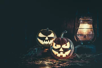 Rolgordijnen Halloween pumpkin with glowing face on a wooden background with candles © Ievgenii Meyer