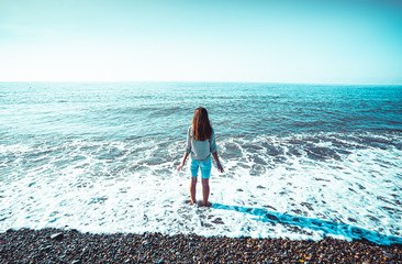 Woman traveler standing in foamy sea water feeling carefree freedom and enjoying sea vacation