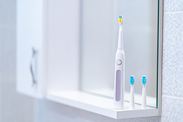 Ultrasonic electric toothbrush with interchangeable nozzles in bathroom at home. Oral hygiene,...
