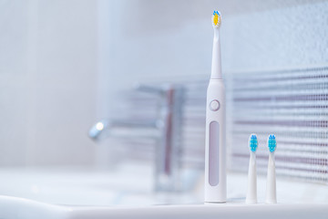 Ultrasonic electric toothbrush with interchangeable nozzles in bathroom at home. Oral hygiene, dental and gum health, healthy teeth.