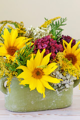 Woman shows how to make floral arrangement with sunflowers and hydrangeas