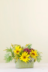 Woman shows how to make floral arrangement with sunflowers and hydrangeas