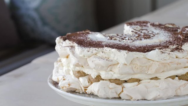 tiramisu meringue. Two layers of meringue with coffee flavour, layered with whipped cream, mascarpone cheese and ladyfingers dipped in coffee. Top is sprinkled with cocoa powder with gorgeous pattern