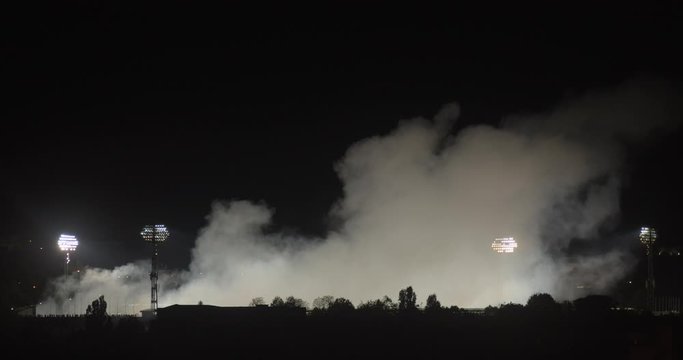 smoke rises above the football stadium at night, total, zoom out