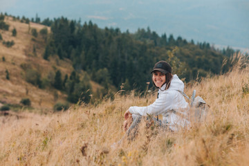 Naklejka na ściany i meble woman sitting on the ground looking at mountains hiking concept
