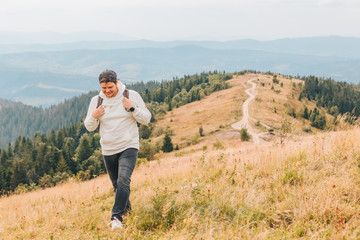 man with backpack hiking by autumn mountains