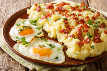 Rustic food mashed potato with bacon and parsley served with fried eggs closeup on a plate. horizontal