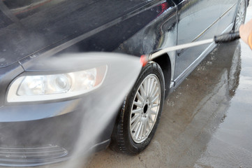 Summer car wash on a contactless self-service car wash. Cleaning a car using high pressure water.
