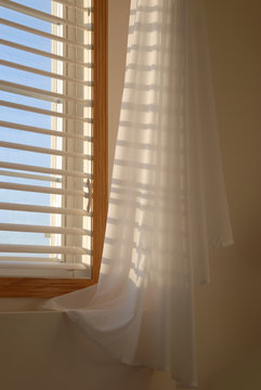 Shadows Of The Evening Sun Coming Through Window Blinds Leaves A Soft Shadow On Draped Sheer Linen Curtains