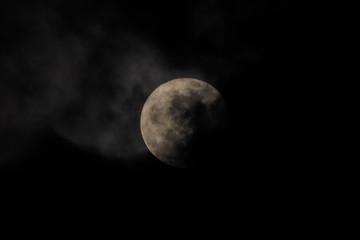 Fototapeta premium full moon scary night, view of full moon rising in dark sky around with dark clouds moving in rainy sky background.