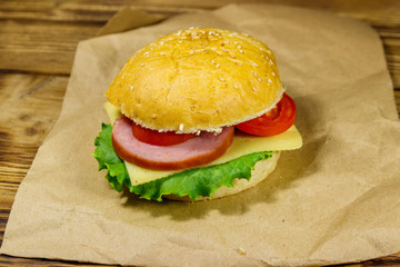 Fresh delicious homemade cheeseburger on brown paper on wooden table
