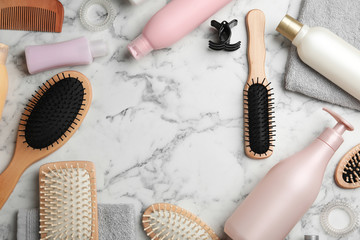 Flat lay composition with hair cosmetic products and tools on marble background. Space for text