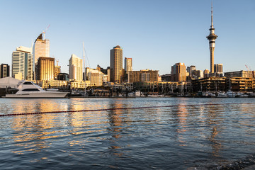 Evening light over the Auckland business and financial district skyline reflecting it the water of the .Viaduct Marina in New Zealand largest city
