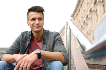 Fototapeta premium Portrait of handsome young man sitting on stairs outdoors