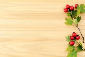 Ripe hawthorn berries on a branch on a wooden surface close-up. Autumn background, top view, copy space