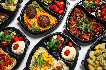 Lunchboxes with different meals on white table, flat lay. Healthy food delivery