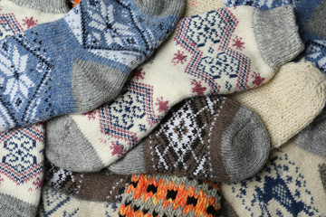 Different knitted woolen socks as background, closeup