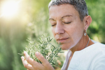 Wellbeing in Nature. Woman Enjoying the scent of Rosemary - obrazy, fototapety, plakaty
